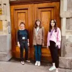 Die drei Referentinnen Jennifer Moss, Alina Meiseberg und Friederike Quint stehen vor einer Eingangstür